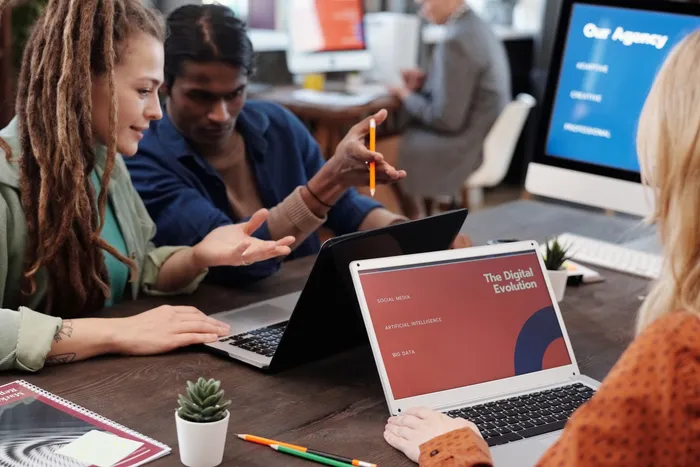 Kreativ-Team arbeitet gemeinsam an Laptops in der Agentur
