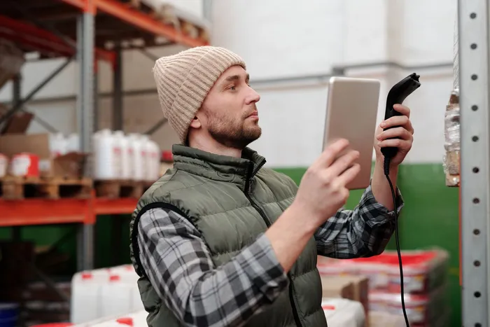 Mitarbeiter erfasst den Warenbestand mit Tablet und Scanner im Lager