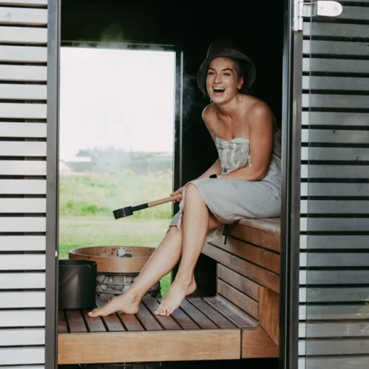 Frau sitzt lachend in der Sauna am Fenster