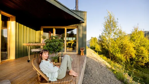 Frau entspannt auf der Terrasse eines Wellness-Lodges mit Blick ins Grüne
